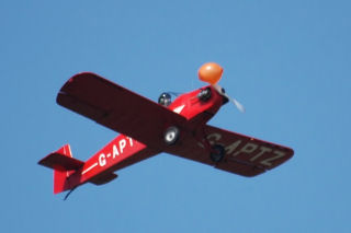 a red plane hitting a small helium balloon