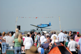 a blue plane flying under a gate